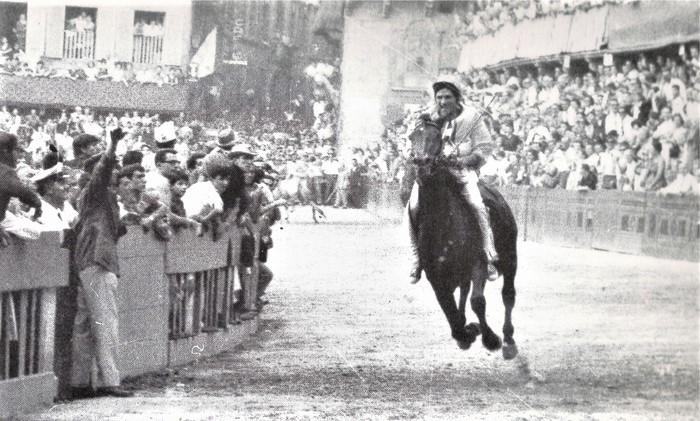 Fantino al galoppo lungo il tufo tra la folla del Palio