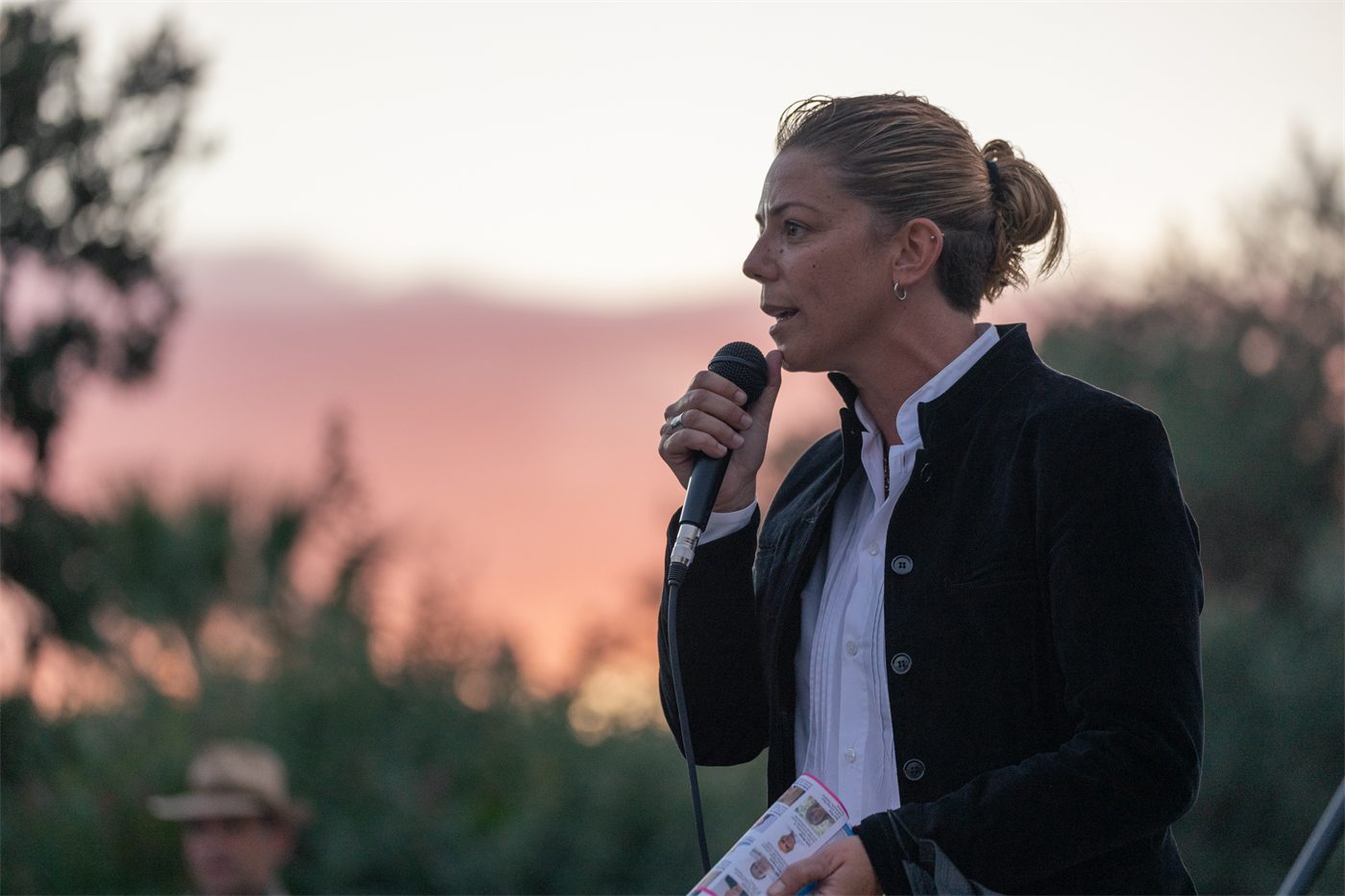 Interviene al microfono durante un incontro pubblico all'aperto